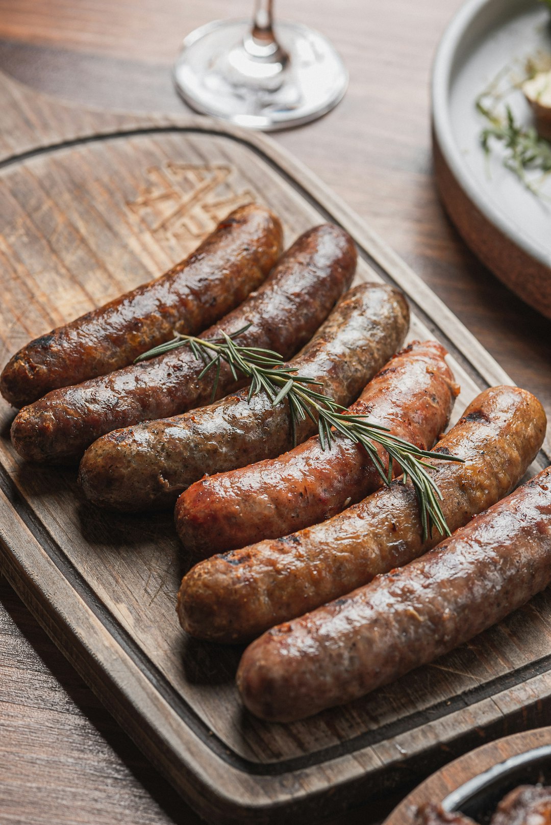 several-grilled-sausages-arranged-on-a-wooden-board-a5ujbtqz6d4